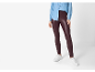 Woman in blue denim shirt and burgundy faux leather leggings, with white sneakers.