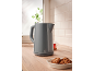 Grey kettle on a wooden countertop with cookies and a cup of tea.