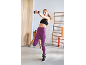 Woman in purple leggings and black sports bra with dumbbells in a gym.