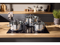 Three stainless steel pots with glass lids on an induction hob in a modern kitchen.