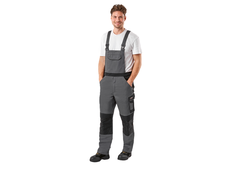 Smiling man in grey and white work overalls with safety shoes.