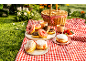 Donuts of various flavors and strawberries at a picnic with a basket and checkered blanket.