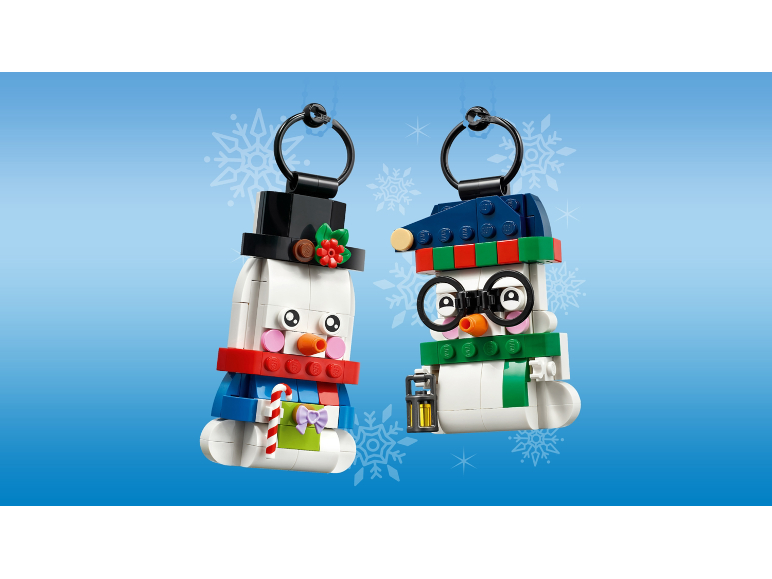 Two snowman building block ornaments with hanging loops on a blue background.