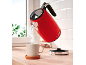 Red kettle pouring water into a mug on a wooden countertop.