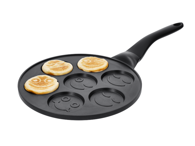 Pancake pan with smiling faces and three cooked pancakes