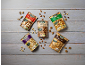 Five bags of nuts, including Brazil nuts, almonds, mixed nuts, cashews, and walnuts, on a wooden surface.