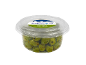 Green Nocellara olives with rosemary and thyme in a clear container.