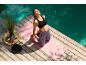 Woman on yoga mat with yoga block by the pool, wearing a sports bra and leggings.