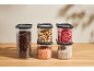 Storage containers with coffee beans, nuts, lentils, dried strawberries, and white beans.