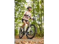 Woman in helmet and pink jacket riding a bicycle on a forest path.