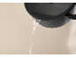 Water pouring from a black pot with a lid.