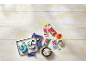 Colorful fondant packages and decorated cakes with flowers and butterflies on light wood.
