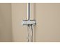 Chrome shower mixer with two flexible hoses against a beige wall.