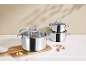 Stainless steel pot set with glass lids, garlic, rosemary, and mushrooms.