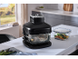 Vacuum marinator with glass container and cooked food on a kitchen counter.