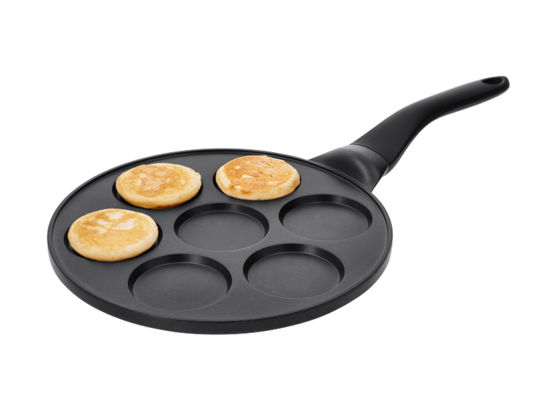 Pancake pan with three golden-brown pancakes and three empty spaces.