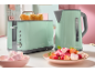 Mint green toaster with toast and matching kettle, with a bowl of marshmallows and a fruit dessert.