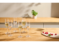 Champagne flutes with sparkling wine and fresh raspberries on a wooden table.