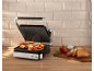 Grilled sandwiches in a sandwich maker with fresh ingredients on the side