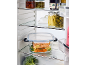 A refrigerator filled with jars of pickled vegetables, jam, and a salmon dish with vegetables.