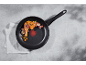 Frying pan with chicken and vegetables on a gray surface.