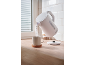 White electric kettle pouring hot water into a mug on a wooden countertop.
