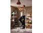 Man on a stepladder changing a lightbulb in a vintage light fixture.
