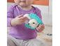 Baby holding a turquoise and white hedgehog rattle.