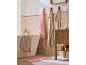 Bathroom with a white bathtub, pink and beige towels, and a wooden cabinet.