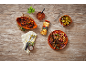 Chickpea dish with lamb chops, peppers, and sauce on a wooden table.