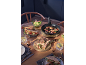 Wooden table with grilled sandwiches, meat skewers in a pan, and fresh salad.