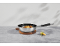 Frying pan with potatoes and rosemary on a wooden cutting board