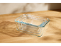 Three stacked rectangular glass containers on a wooden table.