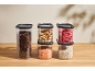 Storage containers with coffee beans, nuts, lentils, dried strawberries, and white beans.
