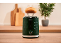 Green toaster with a bun on top, in a kitchen with cutting boards.