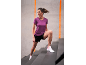 Woman in a purple sports t-shirt and black shorts climbing stairs.