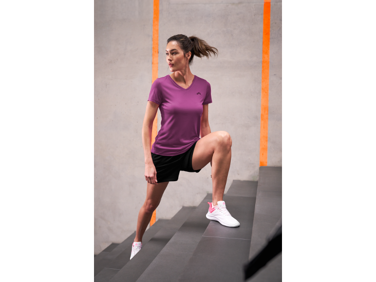 Woman in a purple sports t-shirt and black shorts climbing stairs.