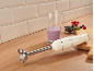 Immersion blender, measuring cup with smoothie, berries on wooden board.