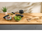 Kitchen counter with food storage bowls, salad, yogurt, and olives.