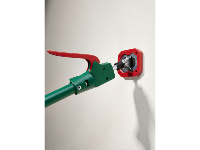 Green and red telescopic support pole touching a wall.