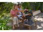 Couple grilling meat and vegetables on a ceramic table barbecue on a patio.