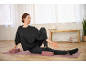 Woman in black CRIVIT Sweatpullover and pants, stretching on yoga mat with yoga blocks.