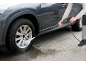Man cleaning a car wheel with a pressure washer.
