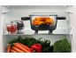 Baking dish with chicken wings, bowl with tomato sauce, and vegetables in a fridge.