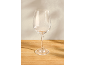Empty wine glass on a wooden table with a light wall in the background.