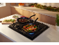 Two pans with Christmas dishes on a gas hob in a kitchen.