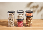 Clear food containers with cereals, legumes, nuts, and dried fruit.