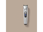Silver hair clipper with a digital display showing 100% charge.