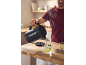 A man pours hot water from a black kettle into a cup of mint and lemon tea.