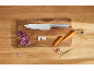 Chef's knife on a wooden cutting board with chopped vegetables and spices.